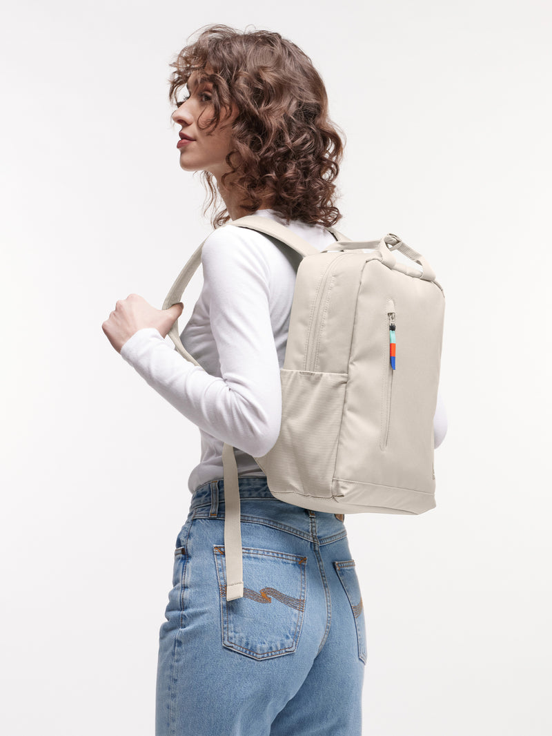 DAYPACK 2.0 Rucksack in soft shell (warmes Cremeweiß) von einer Frau als Rucksack auf dem Rücken getragen.