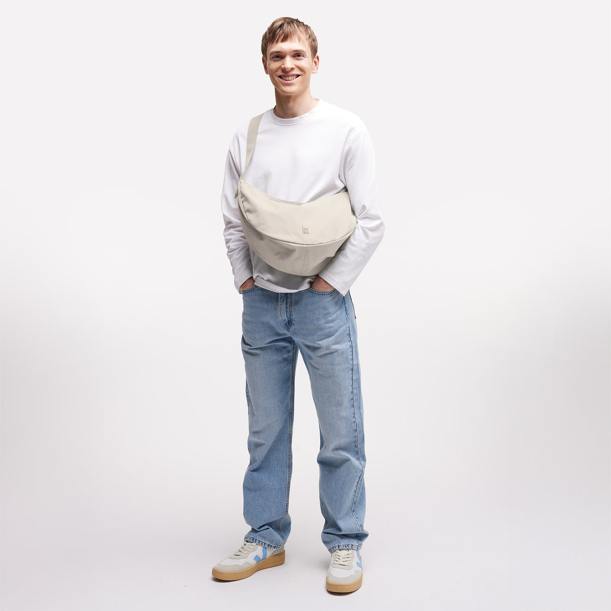 MOON BAG LARGE Tasche in soft shell (warmes Cremeweiß) von einem Mann crossbody getragen.