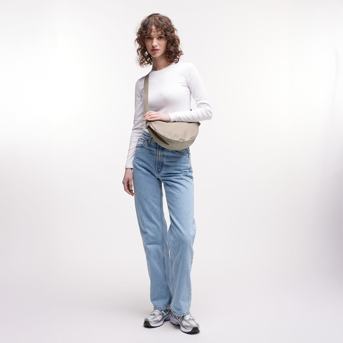 MOON BAG SMALL Tasche in scallop (helles Beige) von einer Frau crossbody getragen.