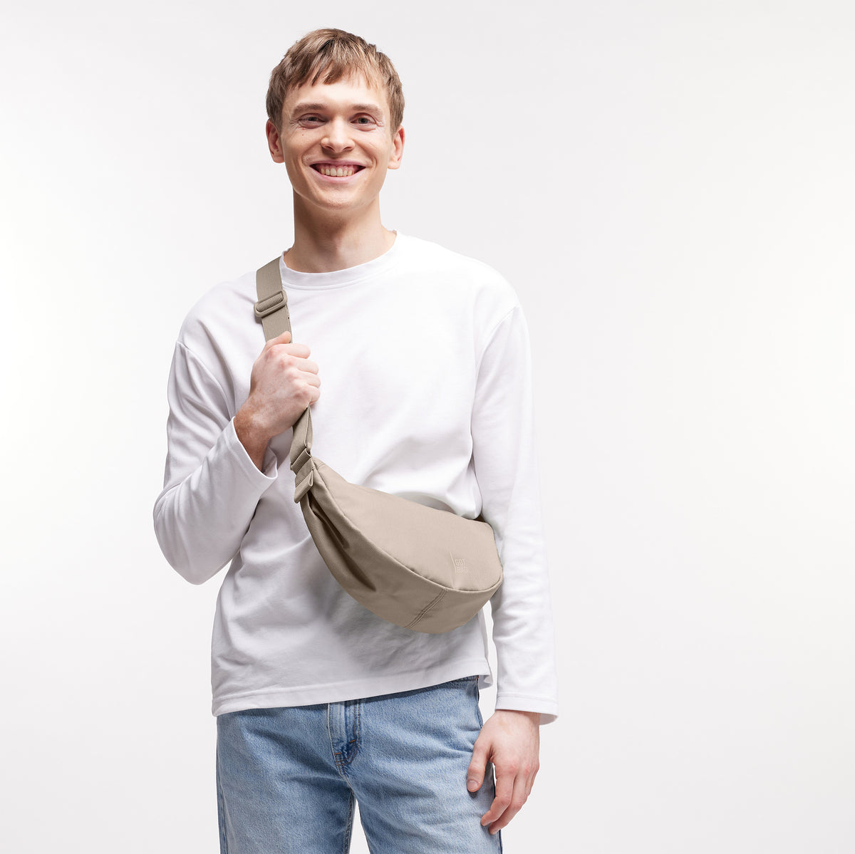 MOON BAG SMALL Tasche in scallop (helles Beige) von einem Mann crossbody getragen.