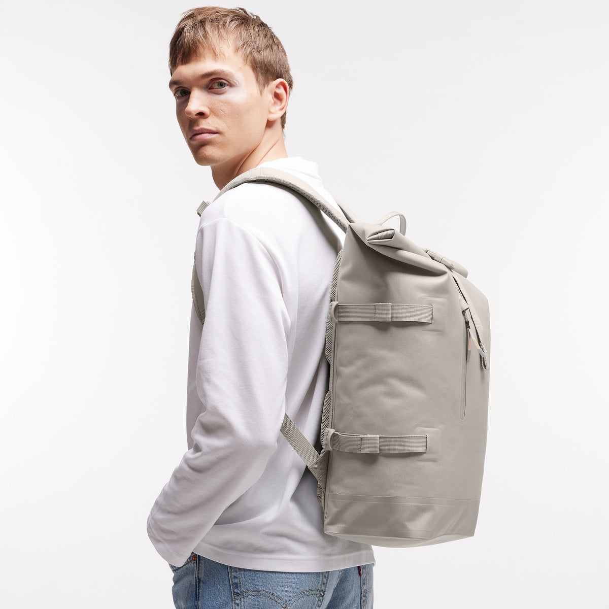 ROLLTOP Monochrome Edition Rucksack in clam (helles, warmes Grau) von einem Mann auf dem Rücken getragen.