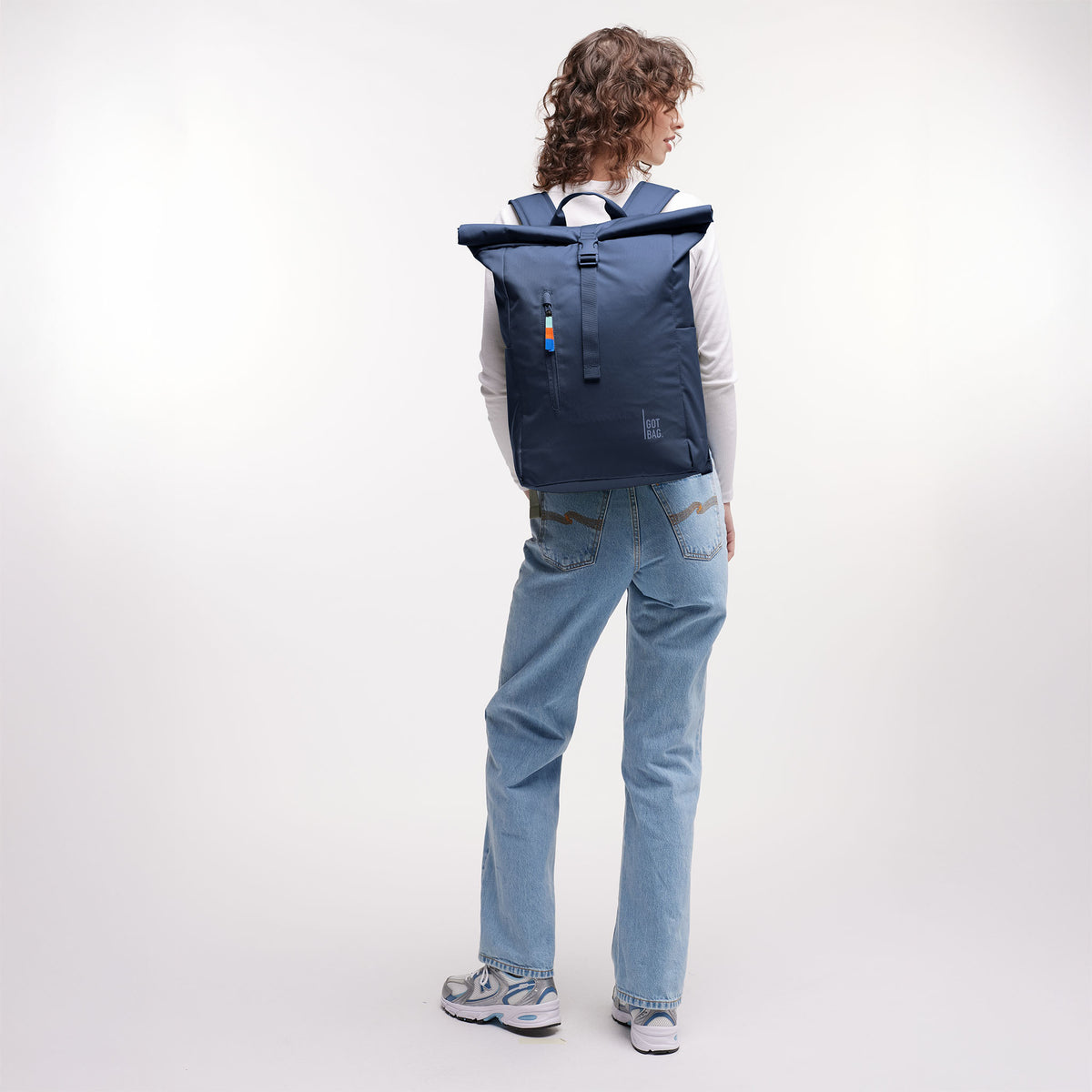 ROLLTOP EASY Rucksack in deep ocean (dunkles Marineblau) von einer Frau auf dem Rücken getragen.
