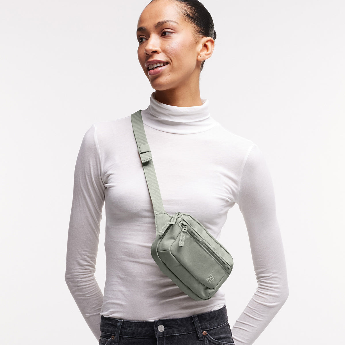 SLING BAG SMALL Tasche in bass (Salbeigrün) von einer Frau crossbody getragen.