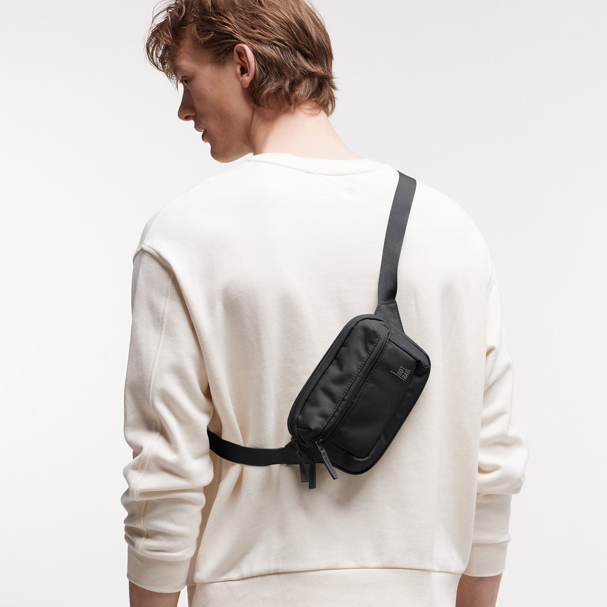 SLING BAG SMALL Tasche in black (Schwarz) von einem Mann crossbody getragen.