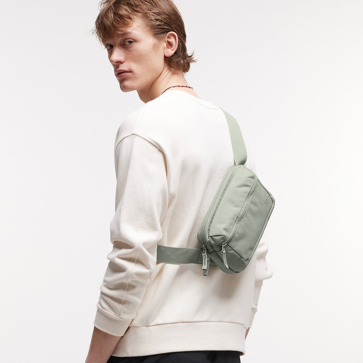 SLING BAG Tasche in bass (Salbeigrün) von einem Mann crossbody getragen.