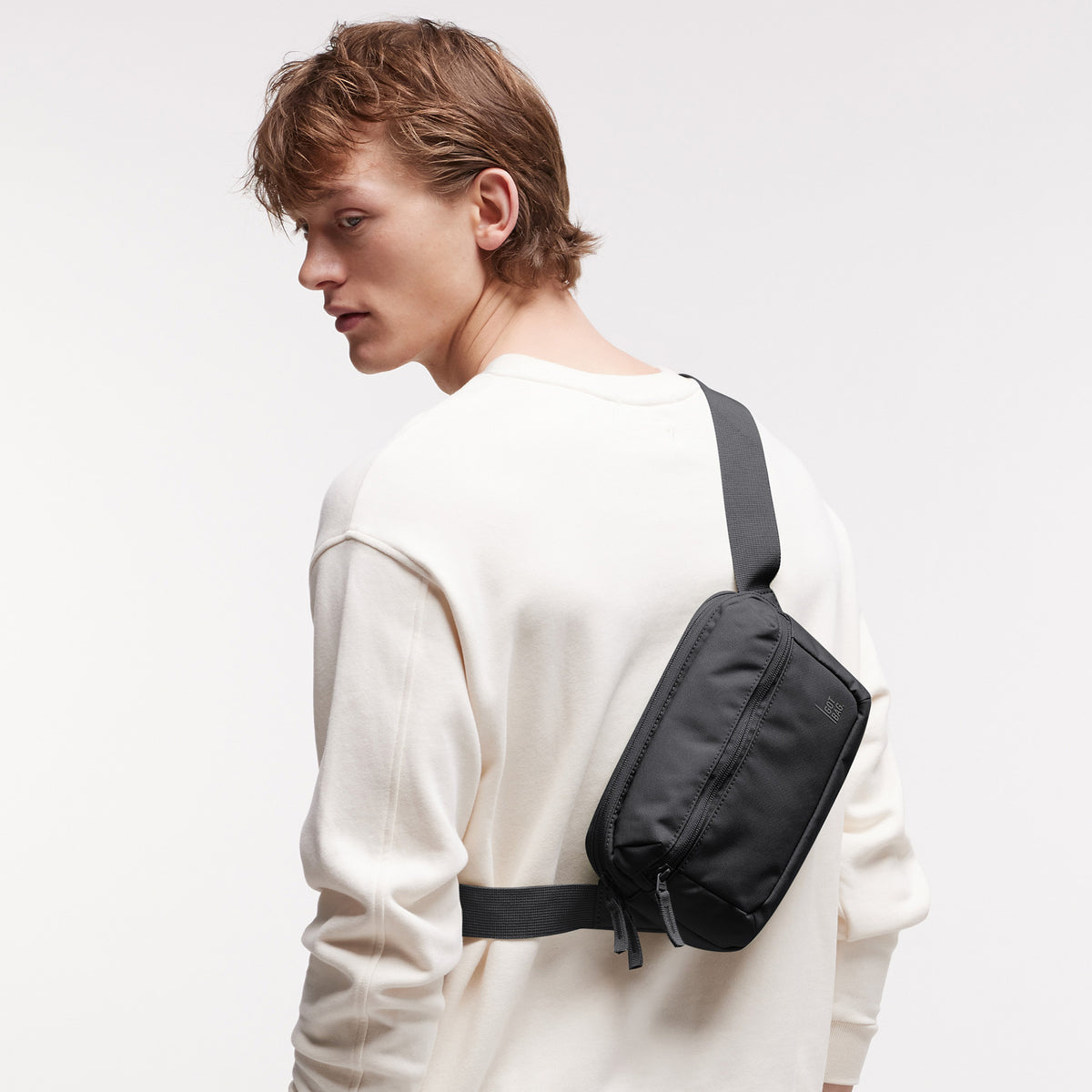 SLING BAG Tasche in black (Schwarz) von einem Mann crossbody auf dem Rücken getragen.