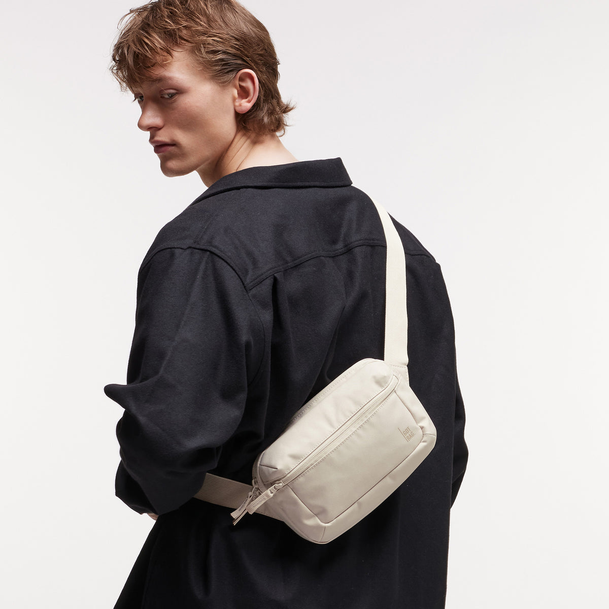 SLING BAG Tasche in soft shell (warmes Cremeweiß) von einem Mann crossbody getragen.