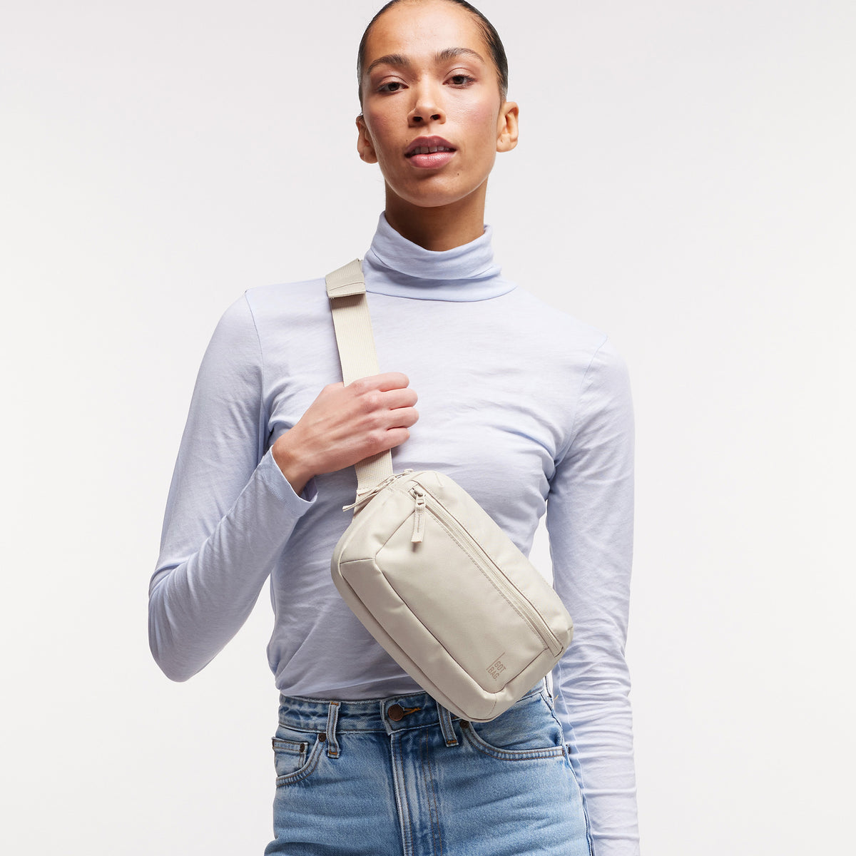 SLING BAG Tasche in soft shell (warmes Cremeweiß) von einer Frau crossbody getragen.