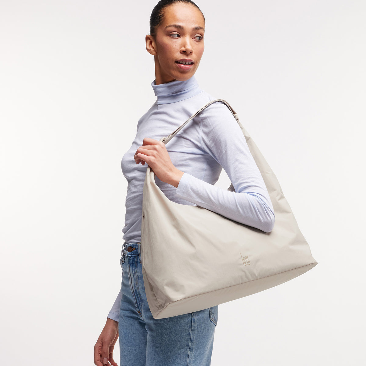 T SHAPE BAG LARGE Tasche in soft shell (warmes Cremeweiß) von einer Frau über der Schulter getragen.