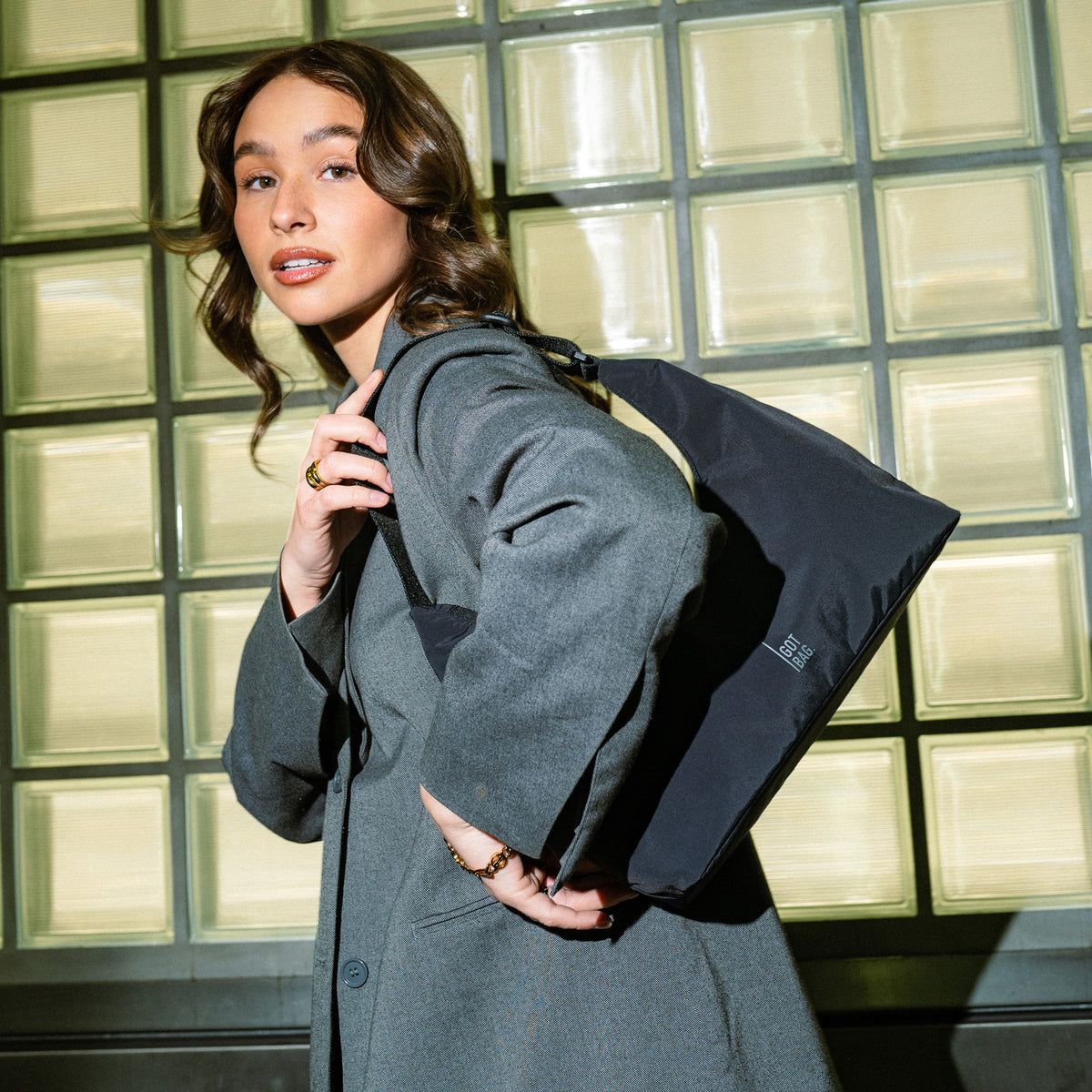 T SHAPE BAG MINI Tasche in black (Schwarz) von einer Frau über der Schulter getragen.