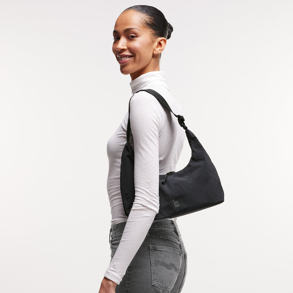 T-SHAPE BAG MINI Tasche in black (Schwarz) von einer Frau über der Schulter getragen.