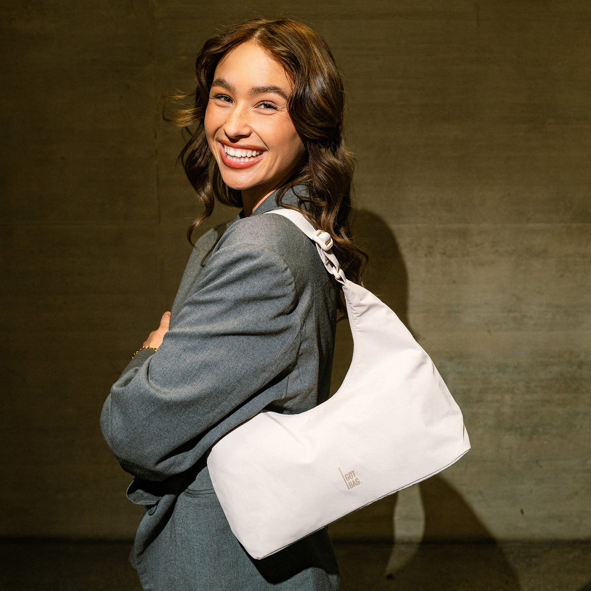T SHAPE BAG MINI Tasche in soft shell (warmes Cremeweiß) von einer Frau über der Schulter getragen.