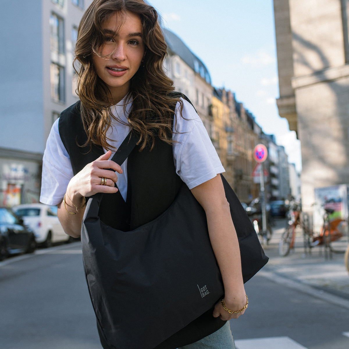 T-SHAPE BAG Tasche in black (Schwarz) von einer Frau über der Schulter getragen.
