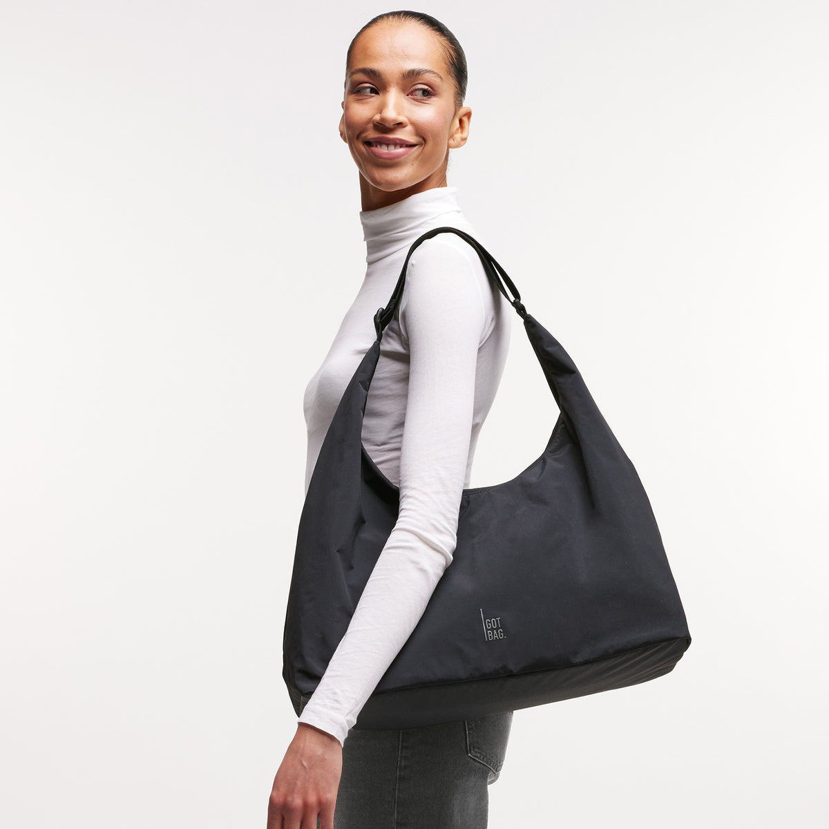 T-SHAPE BAG Monochrome Edition Tasche in black (Schwarz) von einer Frau über der Schulter getragen.