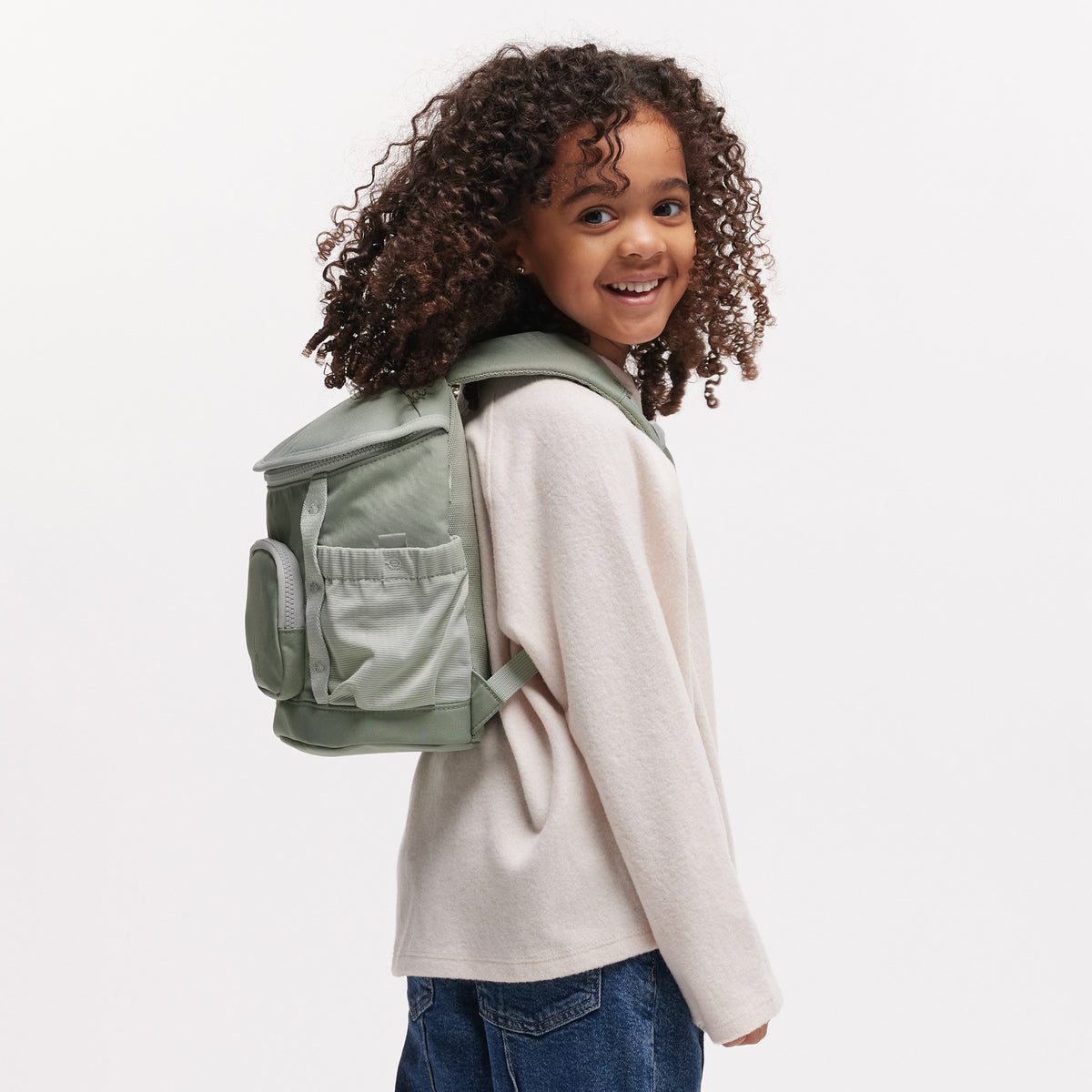 KIDS ADVENTURE DAYPACK Rucksack in bass (Salbeigrün) von einer Frau als Rucksack auf dem Rücken getragen.