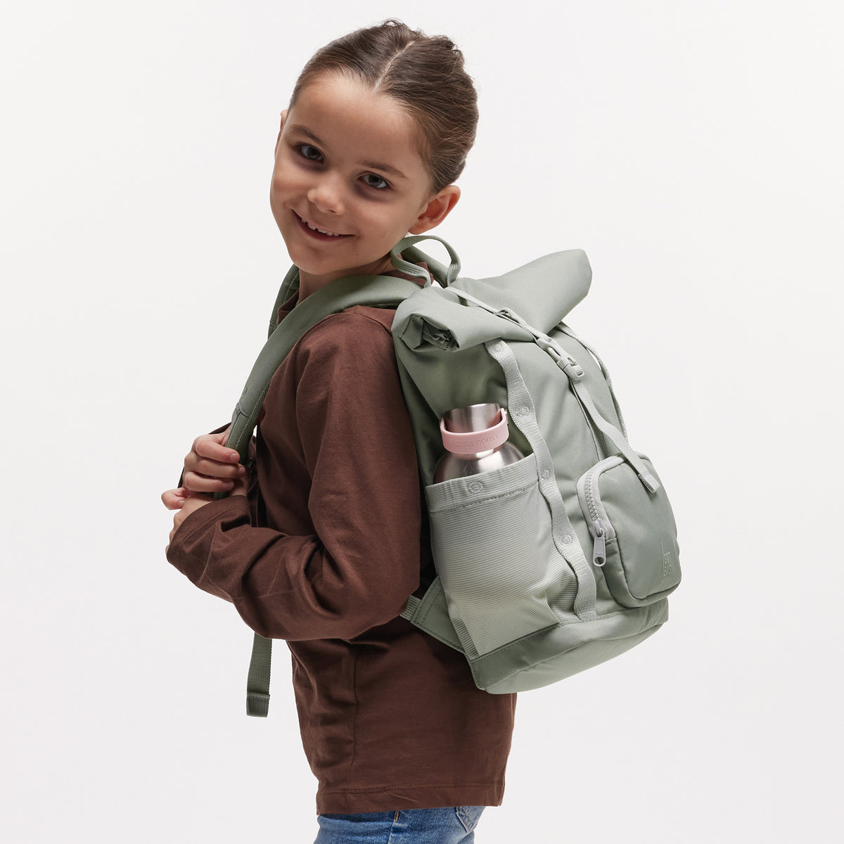 KIDS ADVENTURE ROLLTOP Rucksack in bass (Salbeigrün) von einem Mädchen als Rucksack auf dem Rücken getragen.