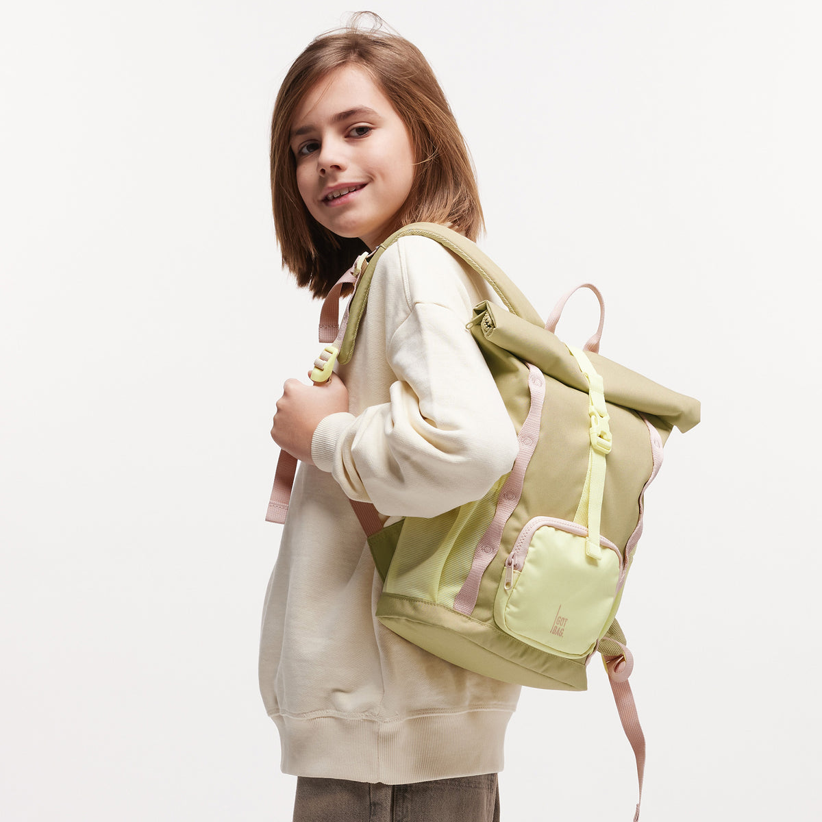 KIDS ADVENTURE ROLLTOP Rucksack in nori (pastellfarbenes Pistaziengrün) von einer Person auf dem Rücken getragen.