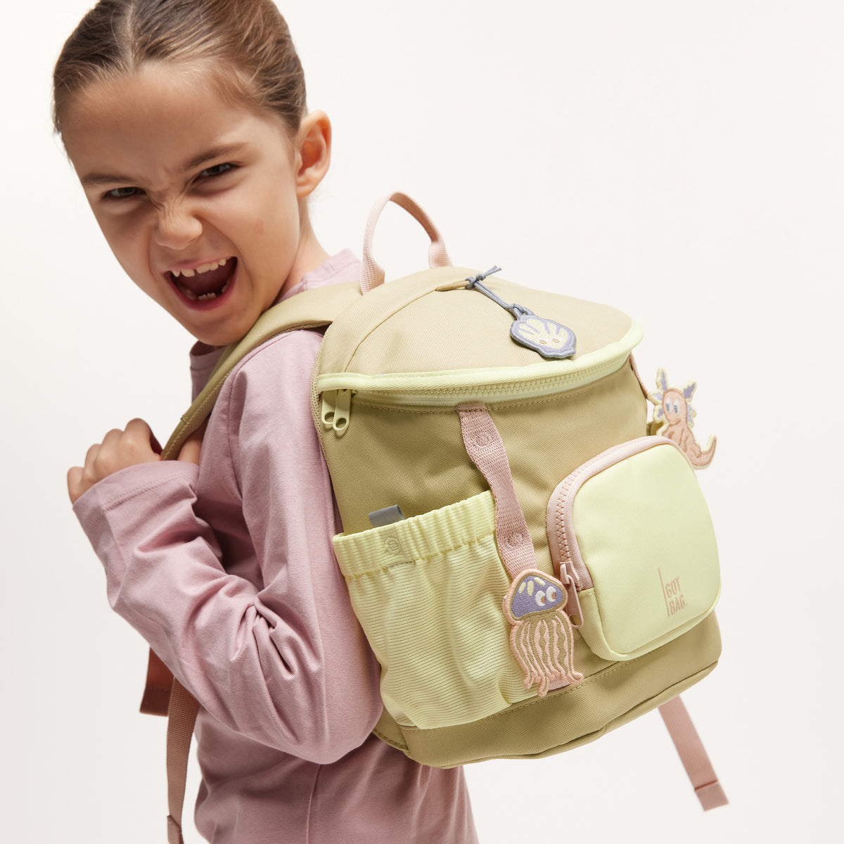 KIDS PATCHES Accessoires in axolotl (gedecktes Altrosa / Mauvefarben) an einem Rucksack, von einer Frau auf dem Rücken getragen.