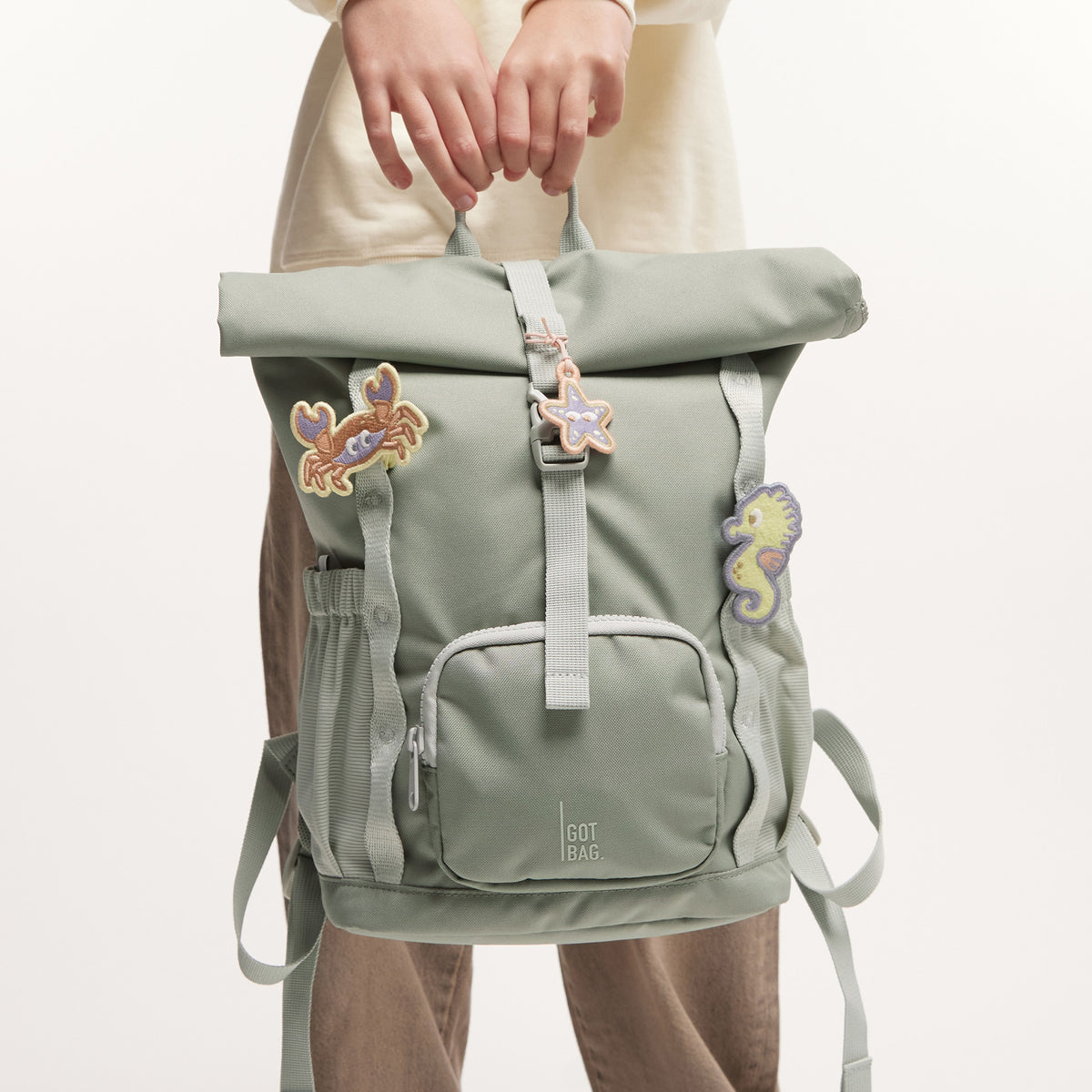 KIDS PATCHES Rucksack in seahorse (graues Pastellrosa) von einer Person in der Hand gehalten.