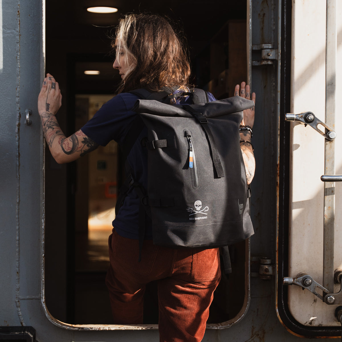 ROLLTOP Rucksack in black (Schwarz) von einer Frau auf dem Rücken getragen.