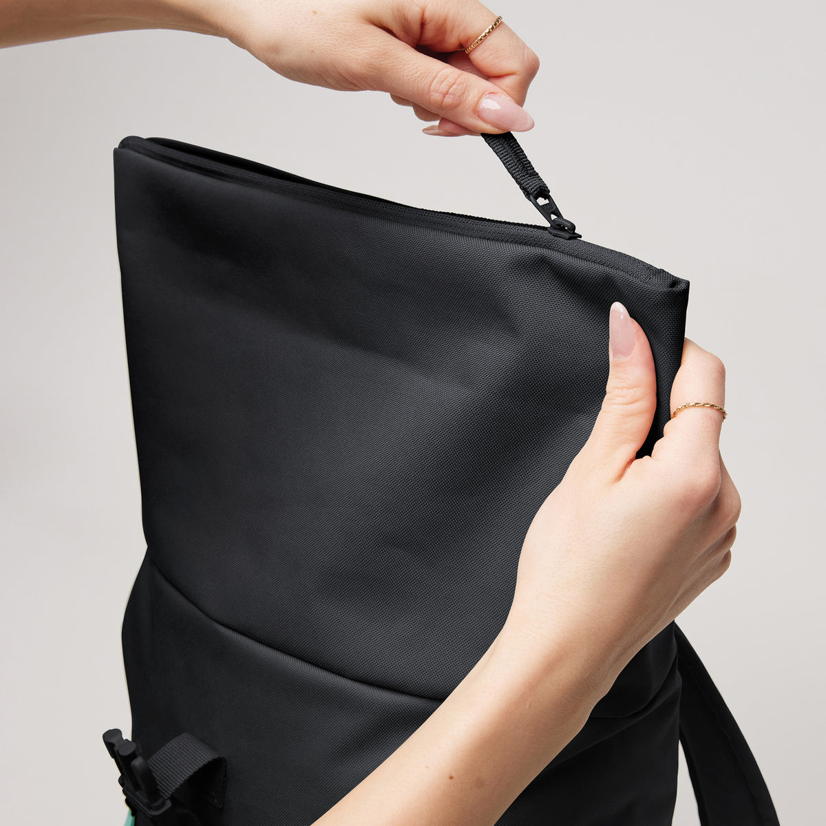 ROLLTOP EASY SMALL Rucksack in black (Schwarz) von einer Frau am Reißverschluss geöffnet.