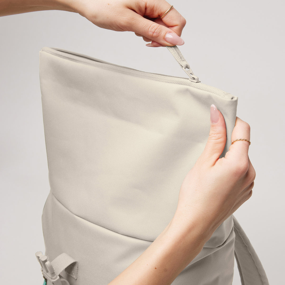 ROLLTOP EASY SMALL Rucksack in soft shell (warmes Cremeweiß) von einer Frau in den Händen gehalten und geöffnet.