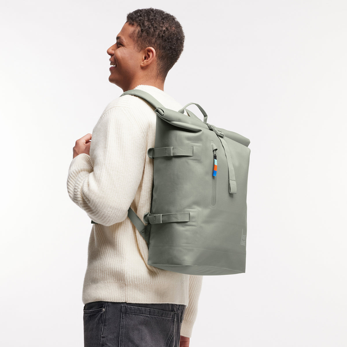 ROLLTOP Rucksack in bass (Salbeigrün) von einem Mann auf dem Rücken getragen.