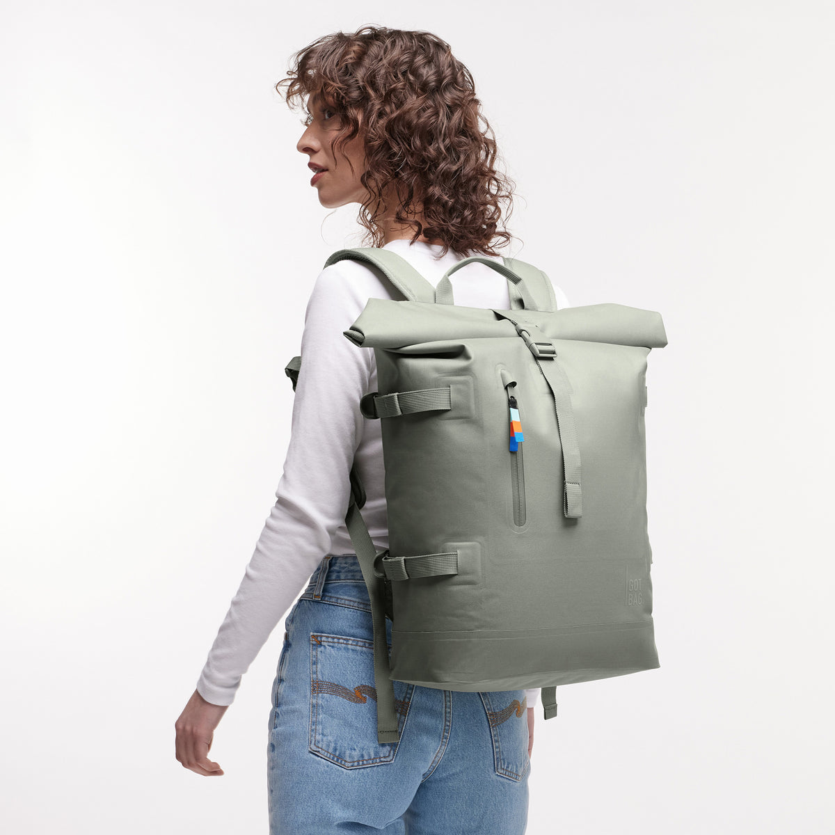 ROLLTOP 2.0 Rucksack in bass (Salbeigrün) von einer Frau als Rucksack auf dem Rücken getragen.