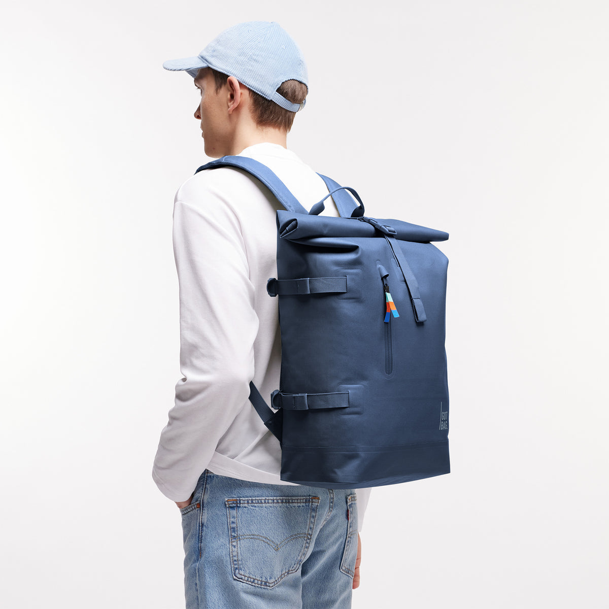 ROLLTOP 2.0 Rucksack, von einem Mann auf dem Rücken getragen, mit vertikalem Reißverschluss und Rollverschluss.