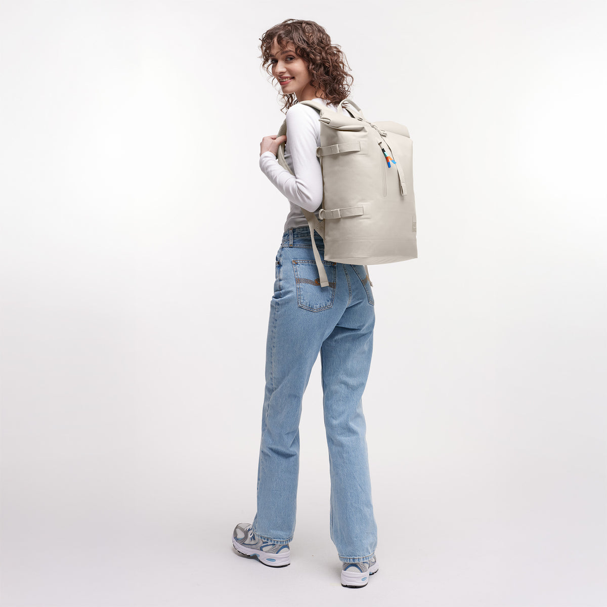 ROLLTOP Rucksack in soft shell (warmes Cremeweiß) von einer Frau als Rucksack auf dem Rücken getragen.