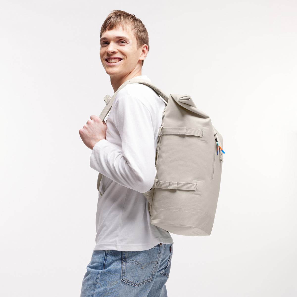 ROLLTOP 2.0 Rucksack in soft shell (warmes Cremeweiß) von einem Mann auf dem Rücken getragen.