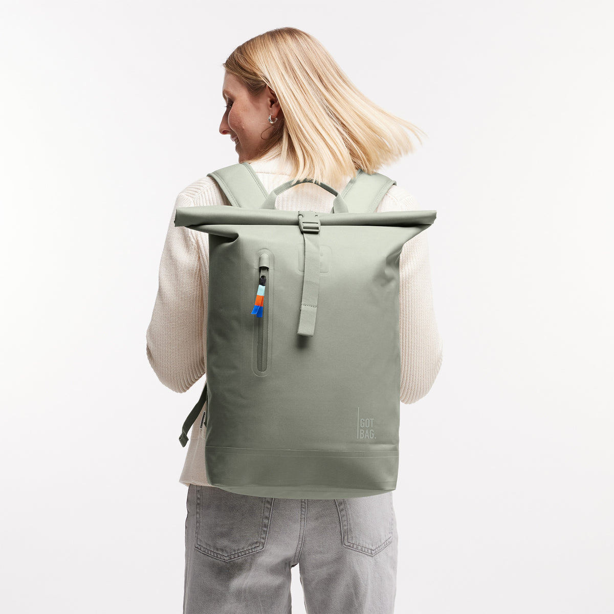 ROLLTOP LITE Rucksack in bass (Salbeigrün) von einer Frau auf dem Rücken getragen.
