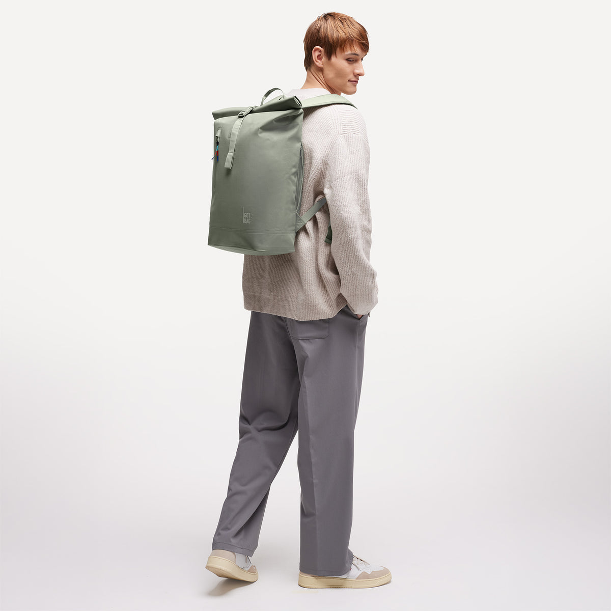 ROLLTOP LITE Rucksack in bass (Salbeigrün) von einem Mann als Rucksack auf dem Rücken getragen.
