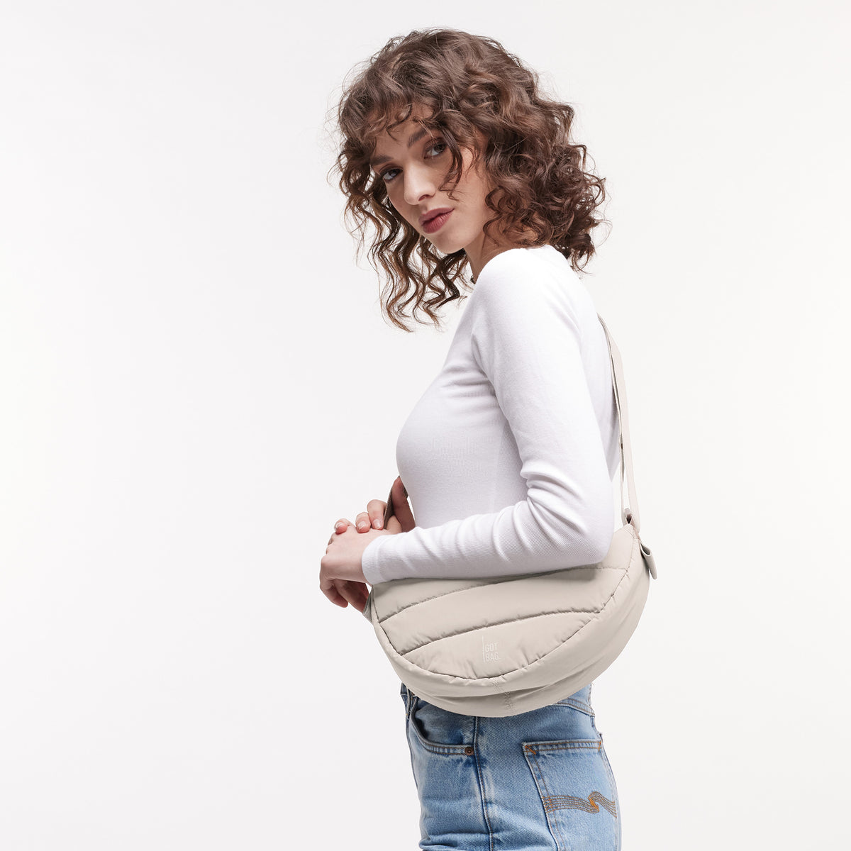 PUFFER MOON BAG SMALL Tasche in scallop (helles Beige) von einer Frau crossbody getragen.