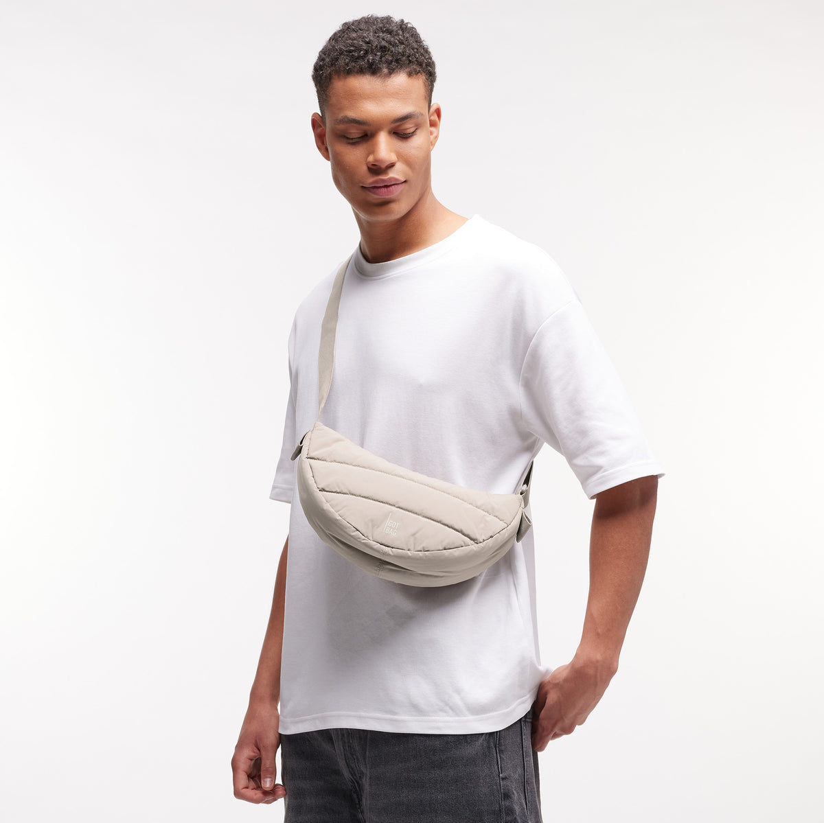 PUFFER MOON BAG SMALL Tasche in scallop (helles Beige) von einem Mann crossbody getragen.