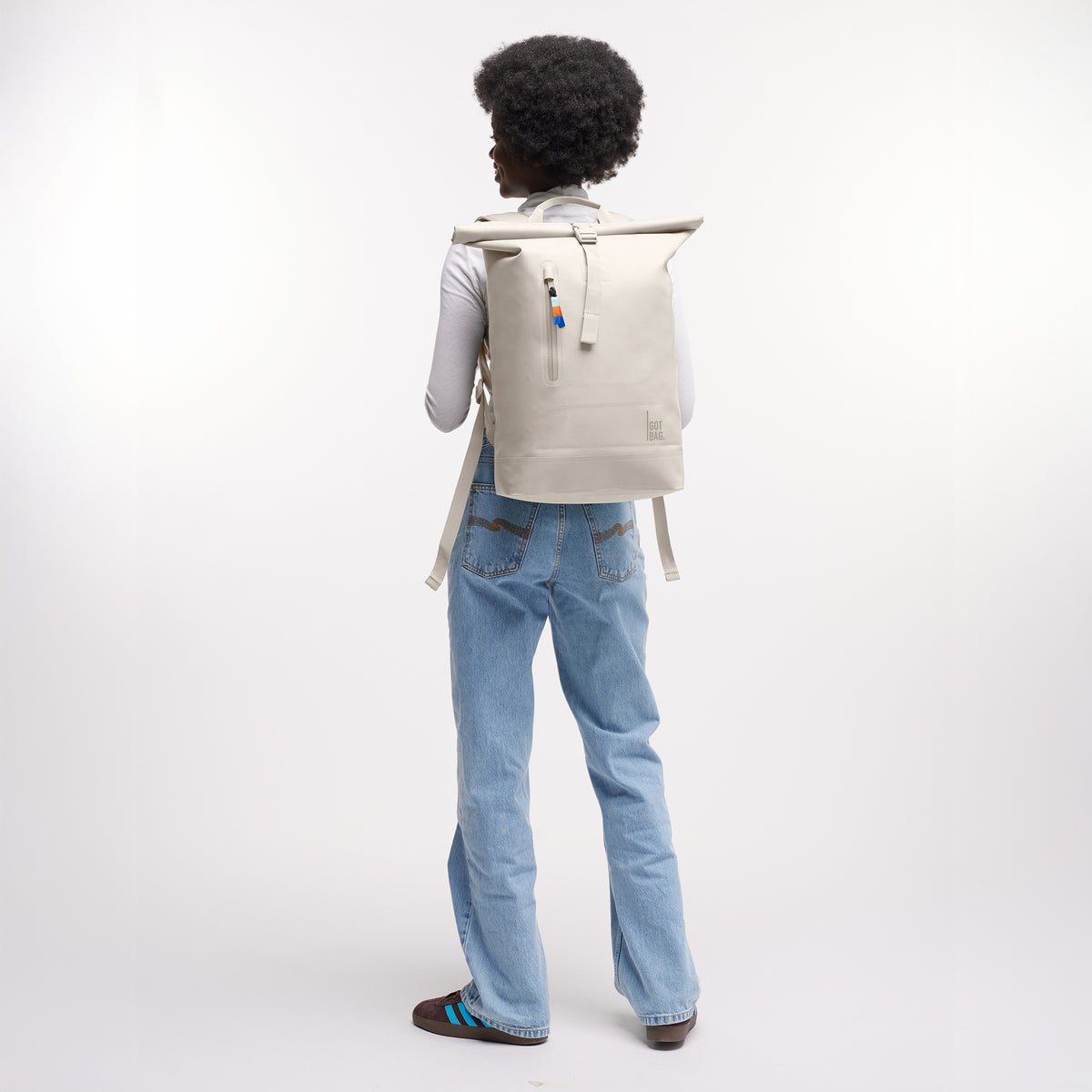 ROLLTOP LITE Rucksack in soft shell (warmes Cremeweiß) von einer Frau als Rucksack auf dem Rücken getragen.