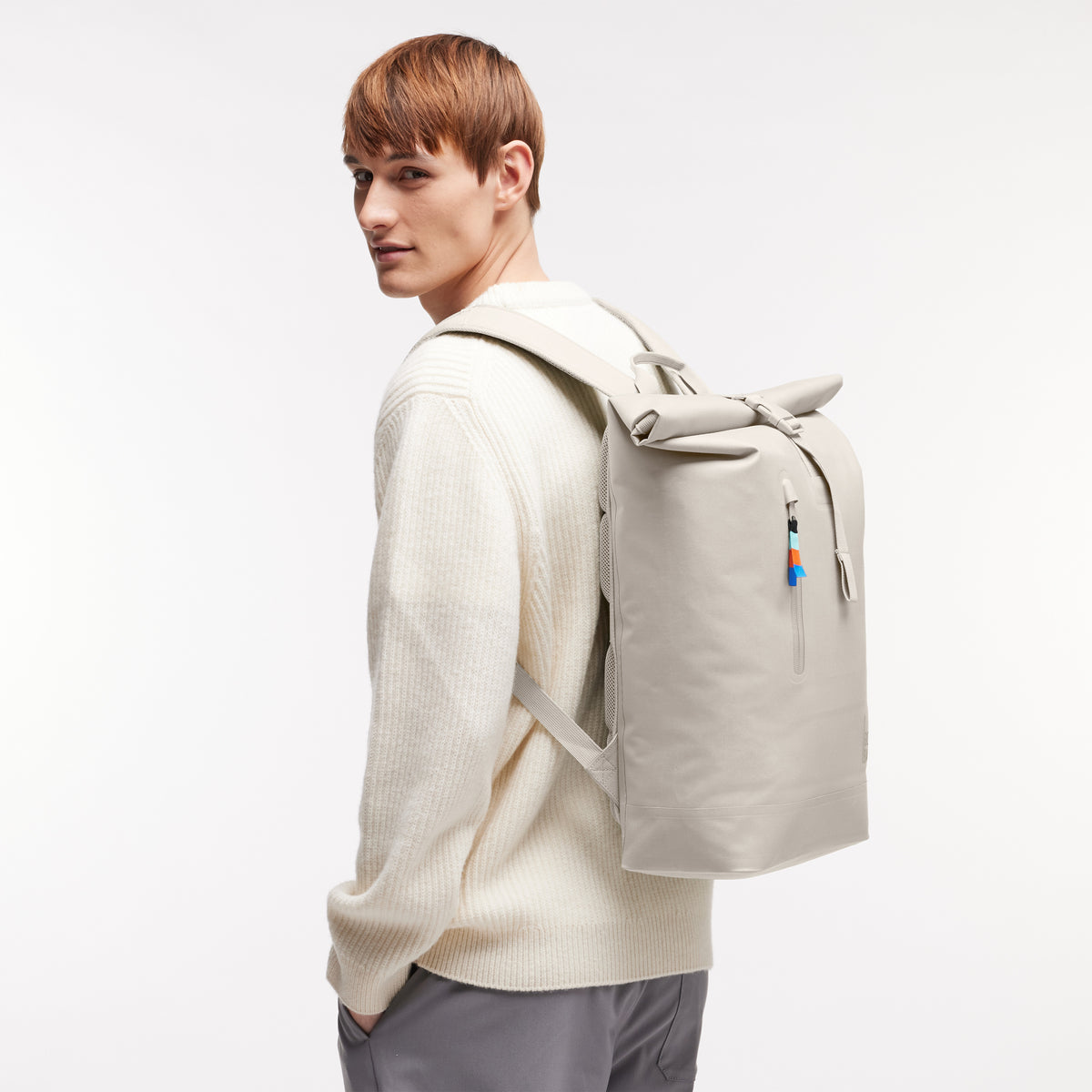 ROLLTOP LITE Rucksack in soft shell (warmes Cremeweiß) von einem Mann als Rucksack auf dem Rücken getragen.