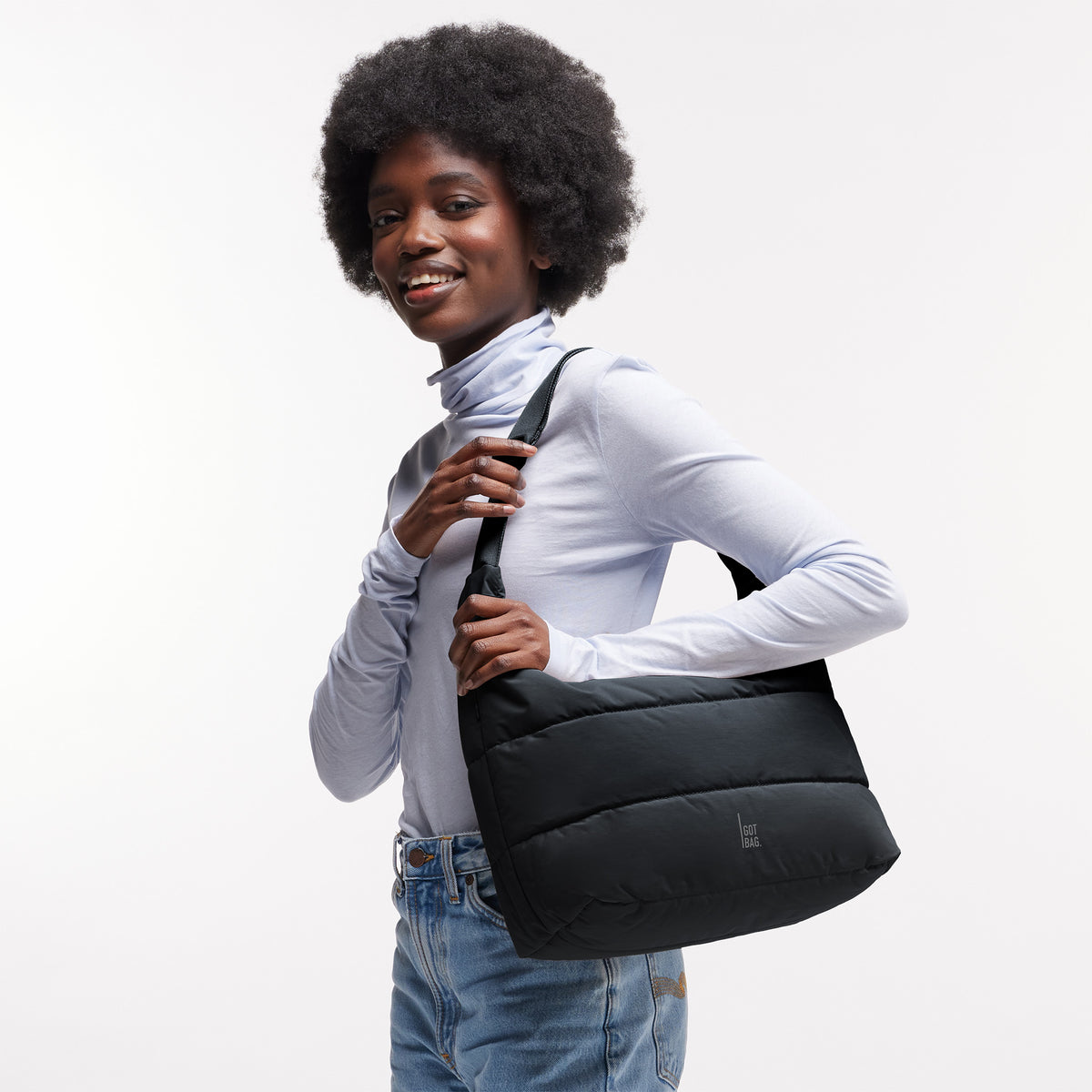 PUFFER SQUARE BAG Tasche in black (Schwarz) von einer Frau über der Schulter getragen.