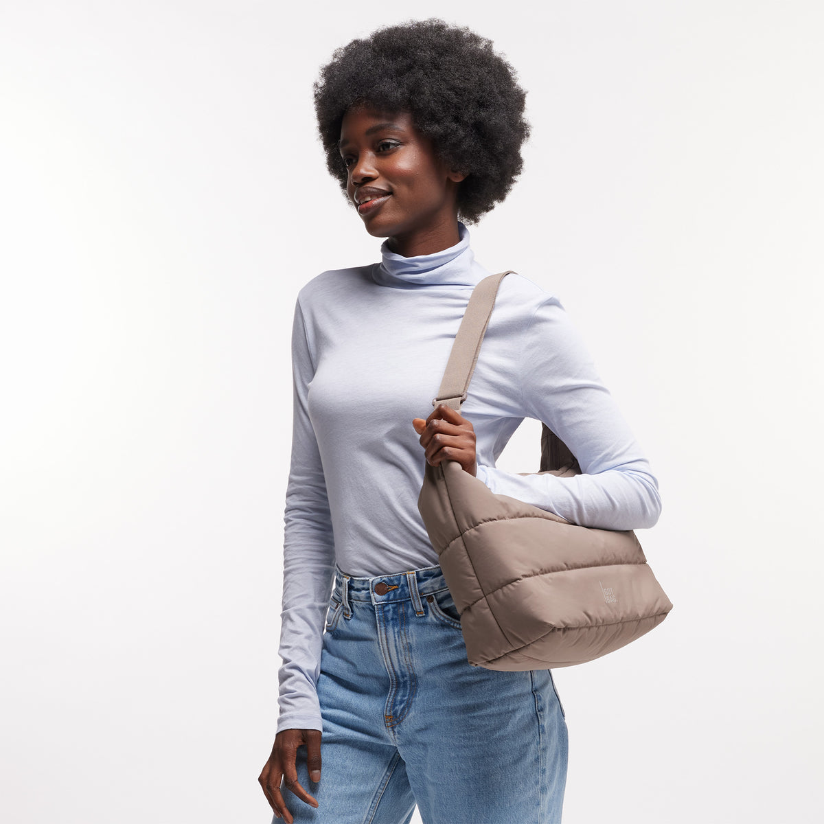 PUFFER SQUARE BAG Tasche in oyster (klassisches Taupe-Braun) von einer Frau über der Schulter getragen.