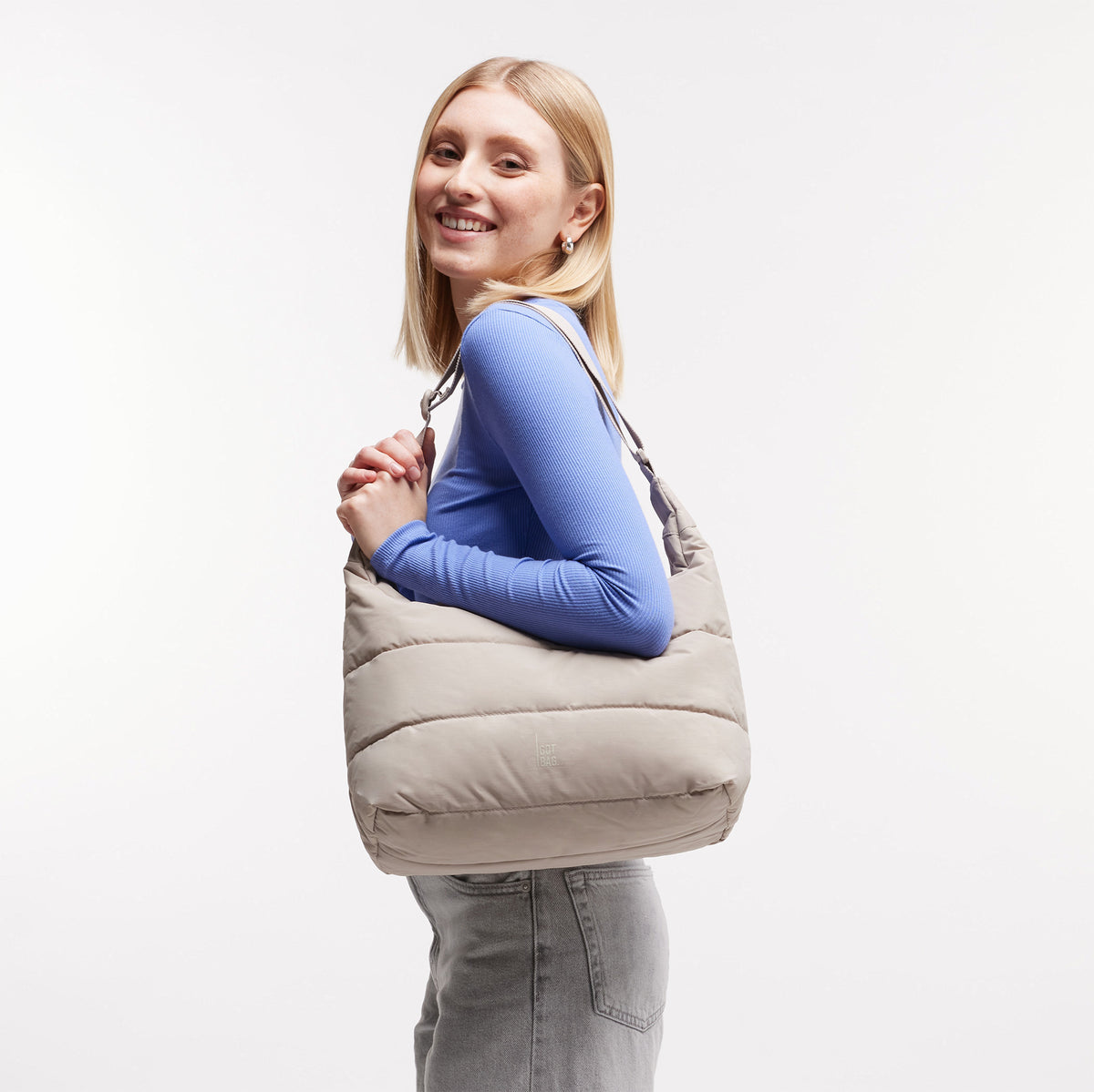 PUFFER SQUARE BAG Tasche in scallop (helles Beige) von einer Frau über der Schulter getragen.