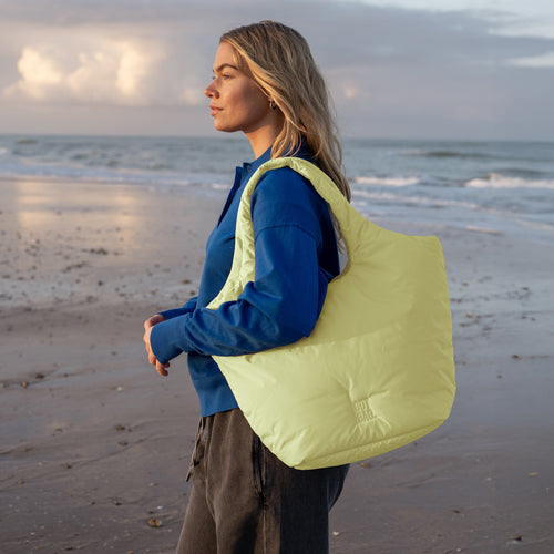 CLOUD TOTE BAG Tasche in sea lemon (zartes Pastellgelb) von einer Frau über der Schulter getragen.