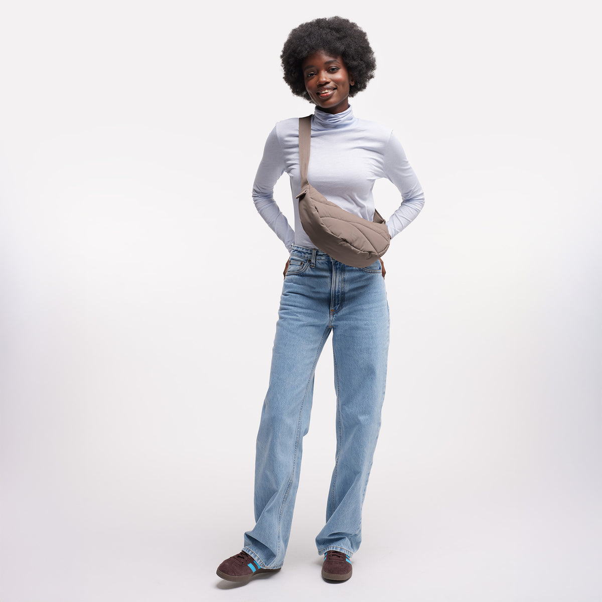 WAVY PUFFER MOON BAG Tasche in oyster (klassisches Taupe-Braun) von einer Frau crossbody getragen.