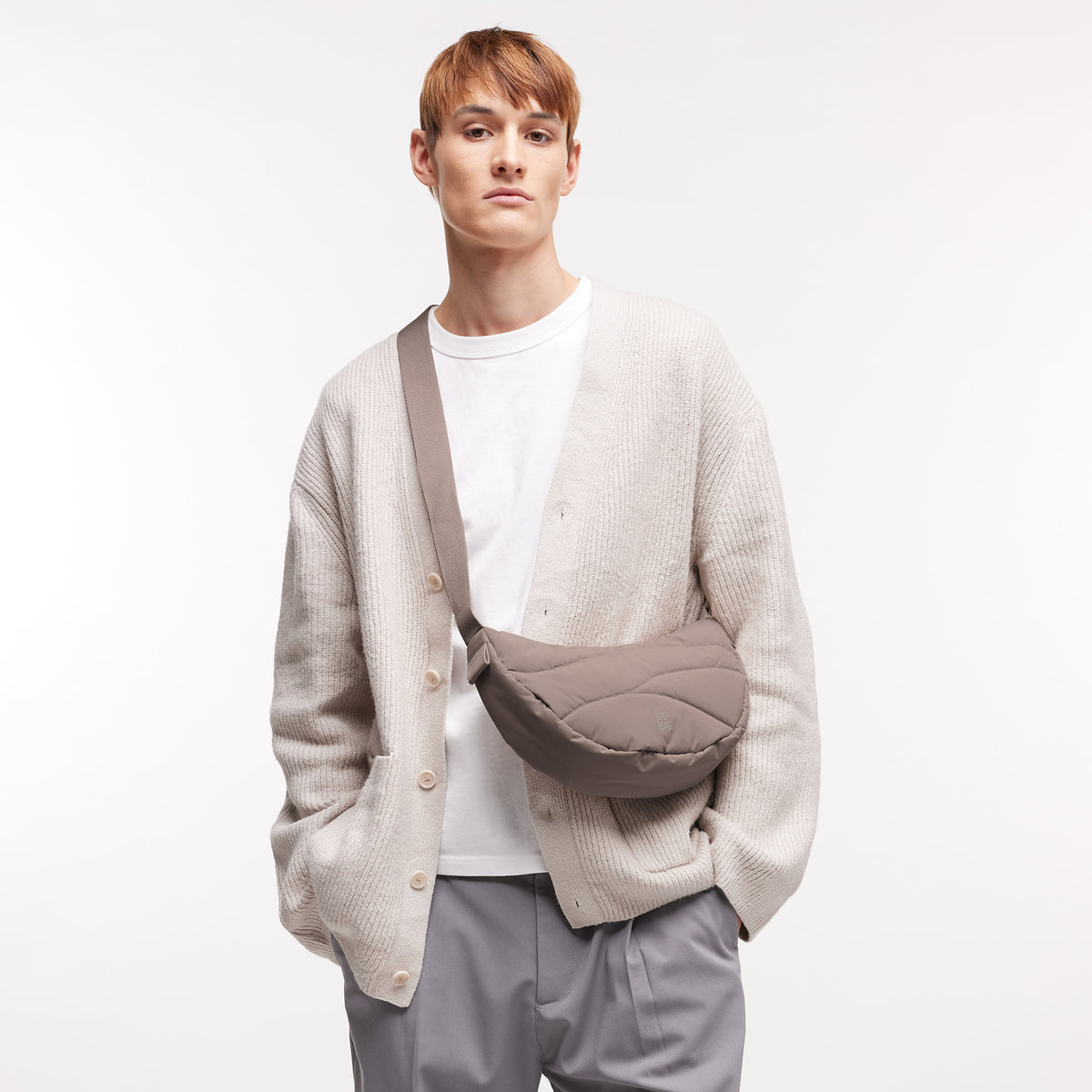 WAVY PUFFER MOON BAG Tasche in oyster (klassisches Taupe-Braun) von einem Mann crossbody getragen.