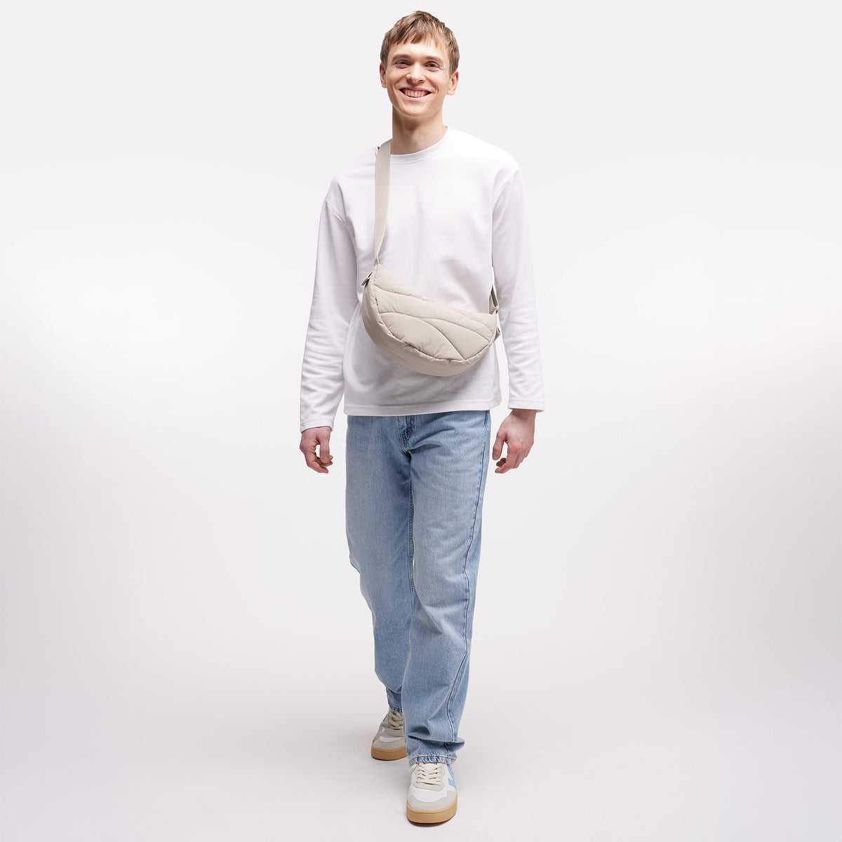WAVY PUFFER MOON BAG Tasche in scallop (helles Beige) von einem Mann crossbody getragen.