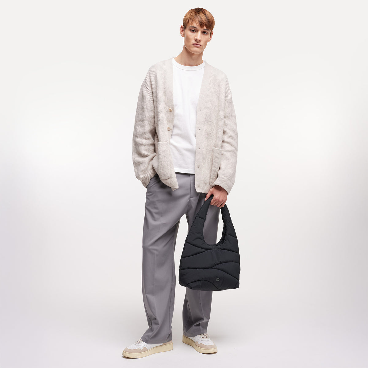 WAVY PUFFER SHOULDER BAG Tasche in black (Schwarz) von einem Mann in der Hand gehalten.