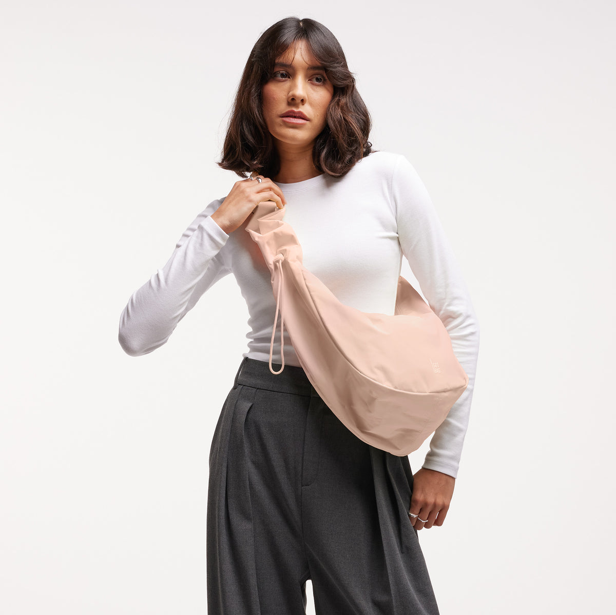 MOON BAG RUFFLE Tasche in pearl (helles Puder-Rosa) von einer Frau über der Schulter getragen.