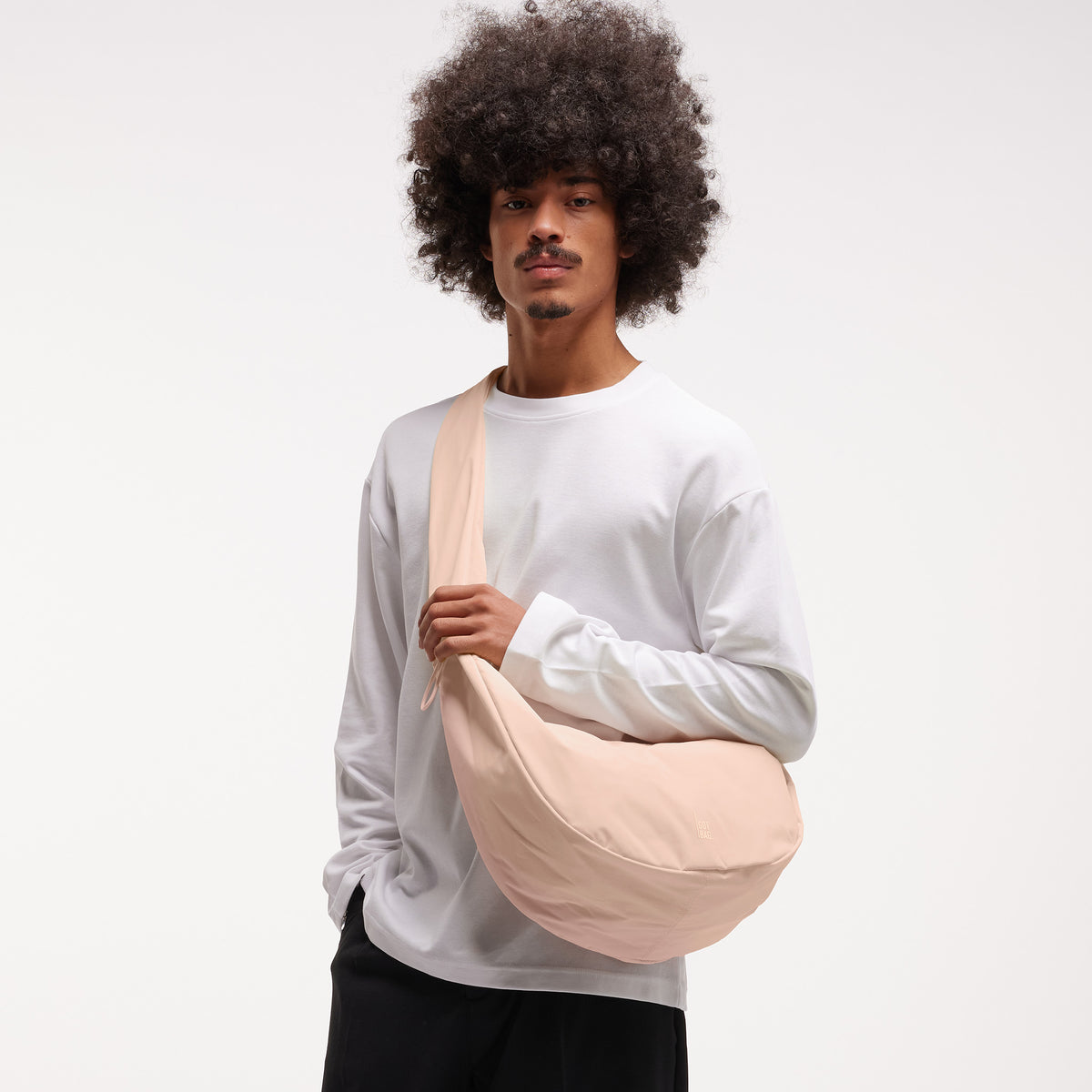 MOON BAG RUFFLE Tasche in pearl (helles Puder-Rosa) von einem Mann über der Schulter getragen.