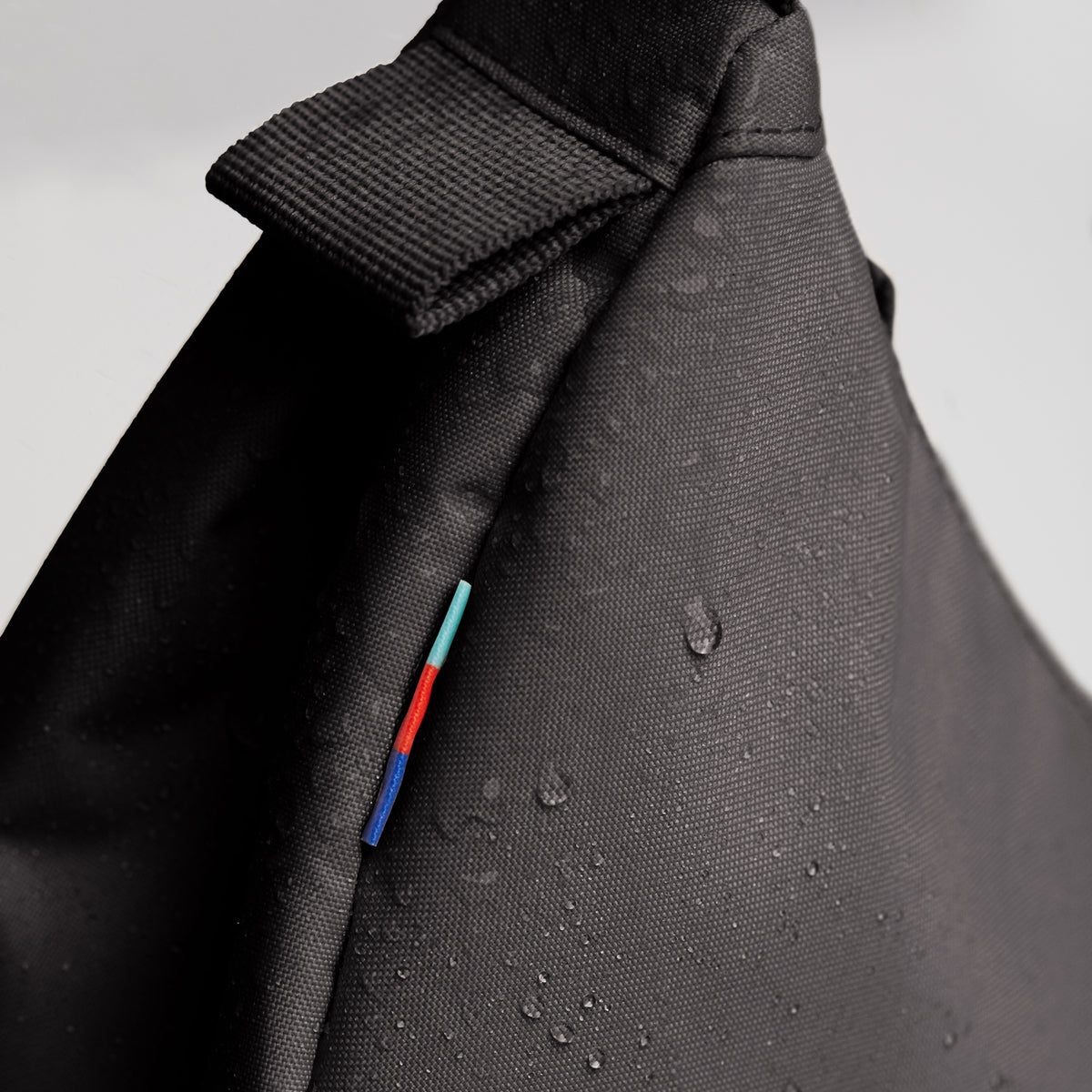 MOON BAG SMALL Tasche in mussel (dunkles Braun-Grau) als Detailaufnahme mit Wassertropfen.
