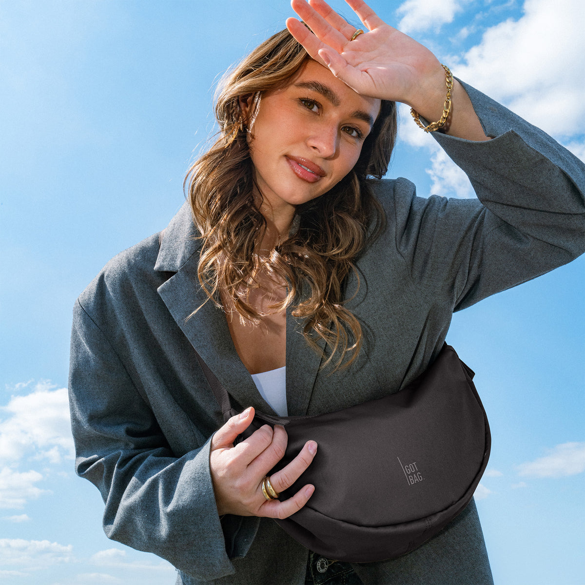 MOON BAG SMALL Tasche in mussel (dunkles Braun-Grau) von einer Frau crossbody getragen.