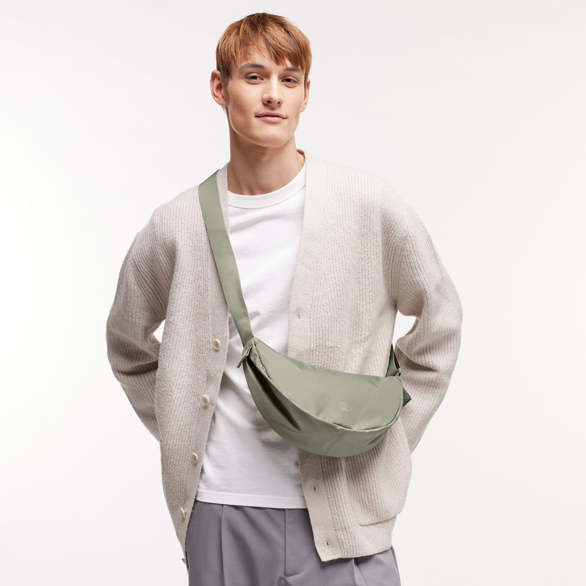 MOON BAG SMALL Tasche in seabed (helles Olivgrün) von einem Mann crossbody getragen.